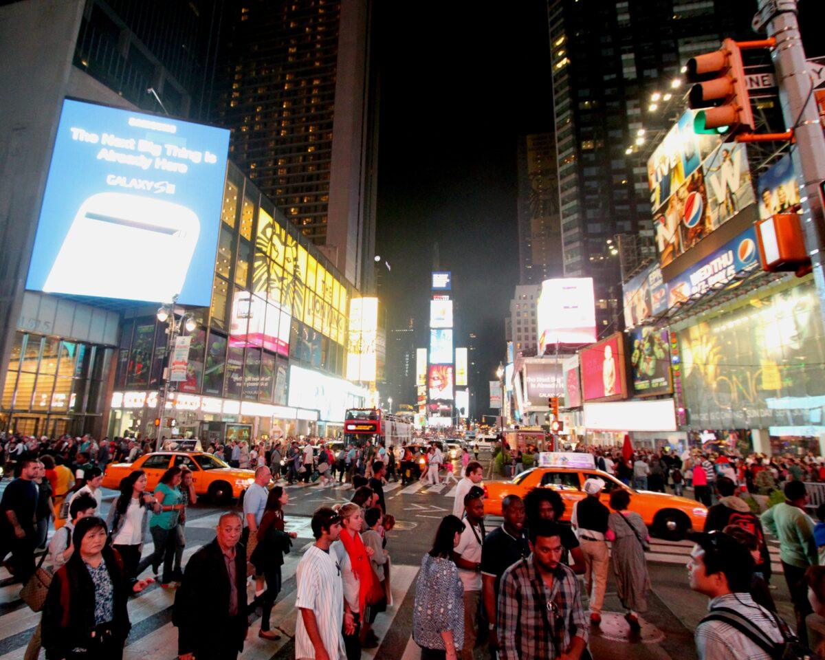 Times Square at night: crowd, yellow taxis and giant screens