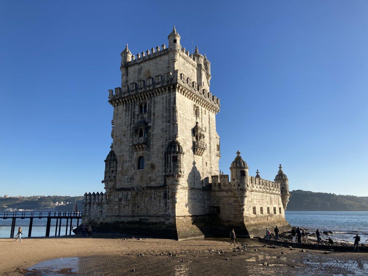 Belém Tower at low tide with walkers on the beach
