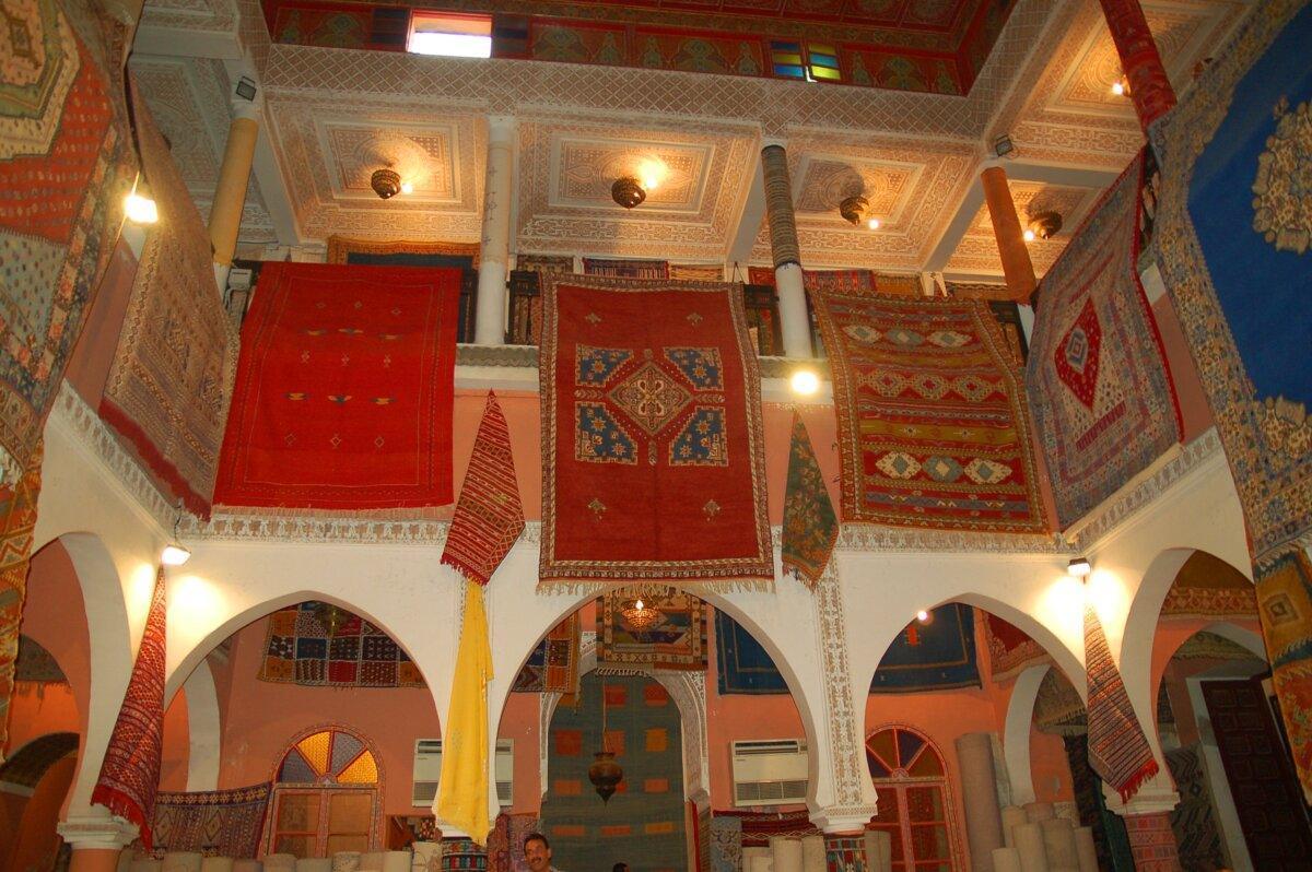 Intérieur d’un souk de Marrakech avec tapis suspendus et arcades