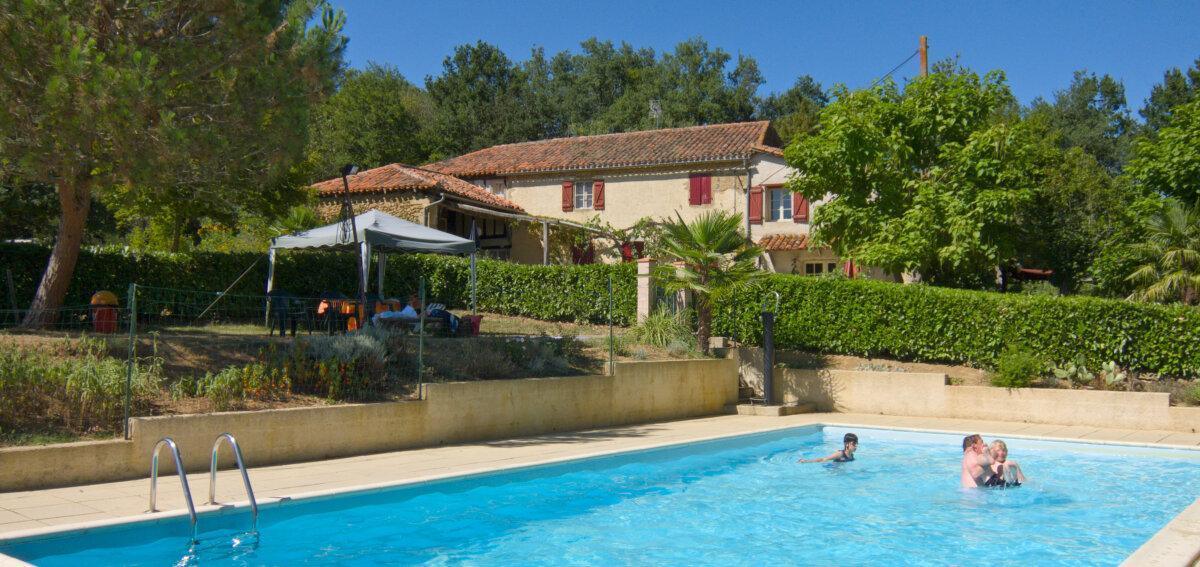 Piscina al aire libre en un camping, con tumbonas y vegetación