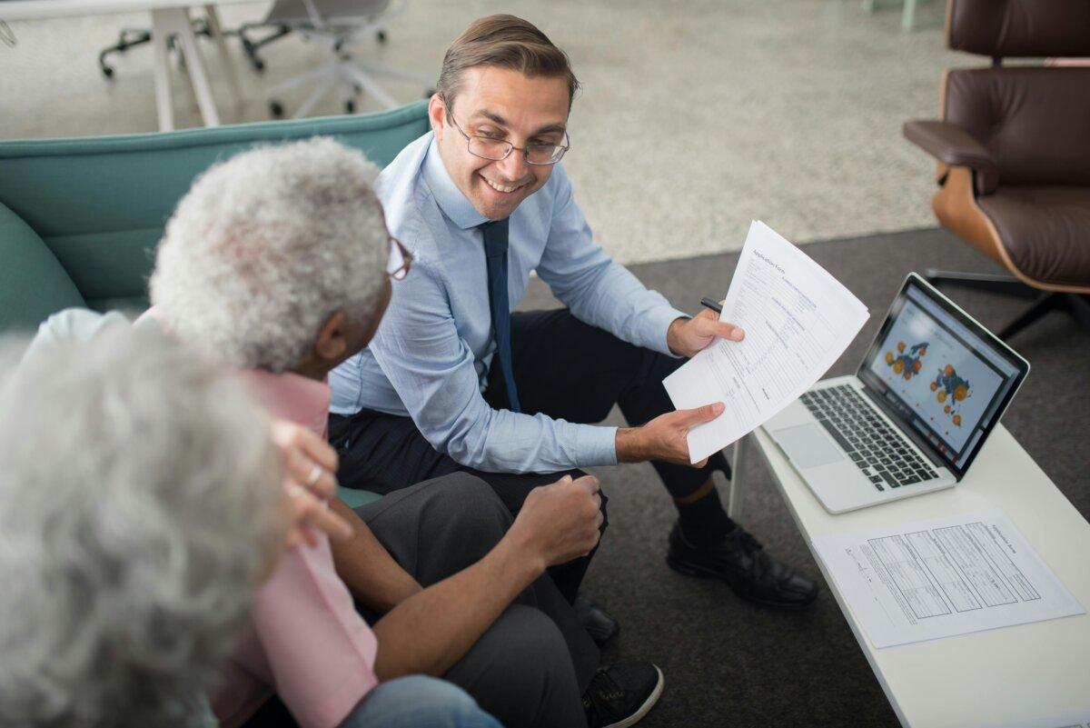 Conseiller patrimonial présentant des documents à un couple senior lors d'un entretien en bureau
