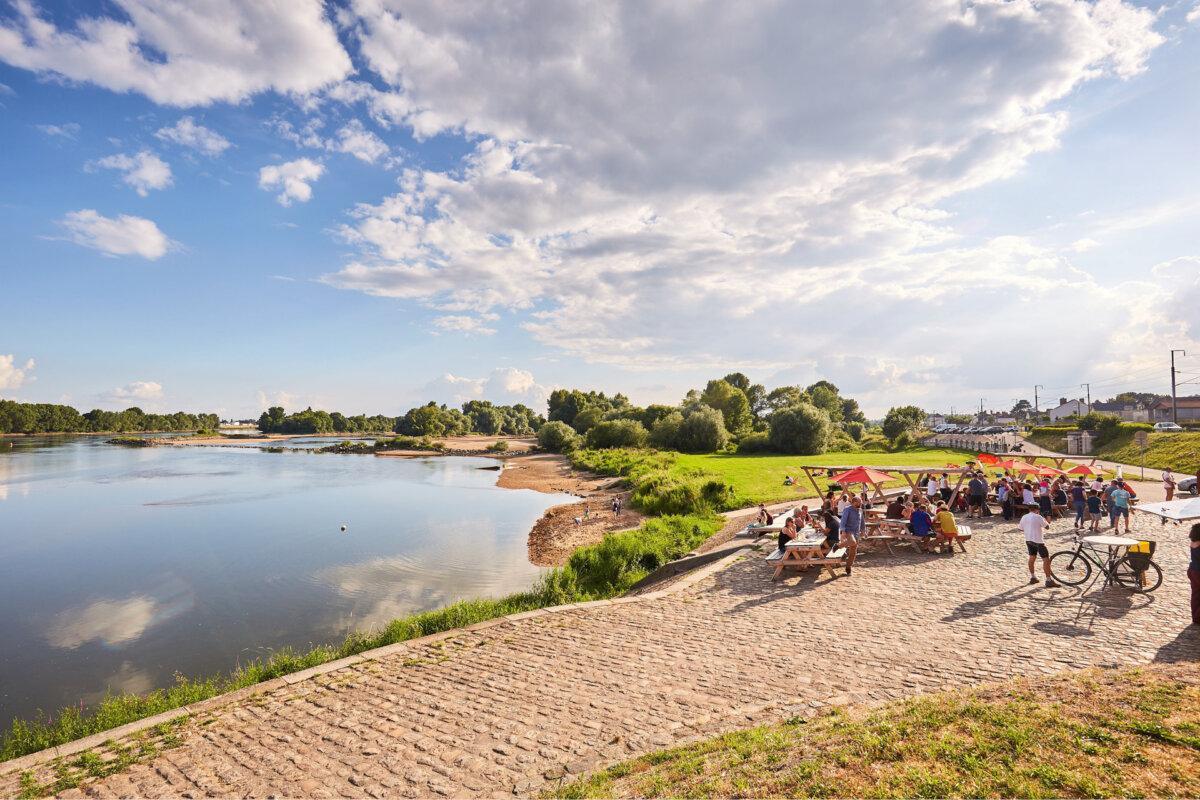 Ufer der Loire mit Picknicktischen, ruhigem Wasser und hellem Himmel