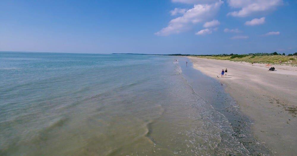 Gran playa de arena bordeada de dunas bajo un cielo azul en la Bahía de Somme