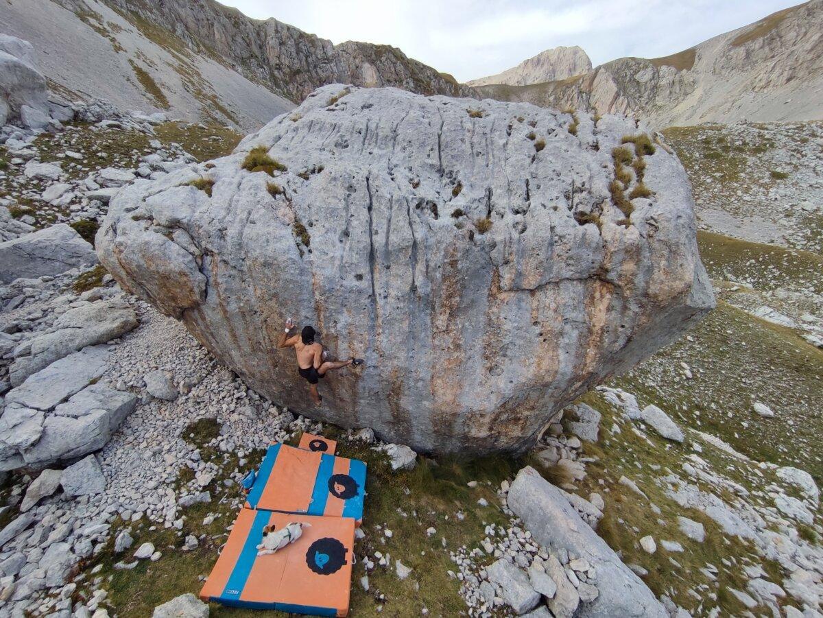 Grimpeur en bloc sur un gros rocher avec crash pads au sol